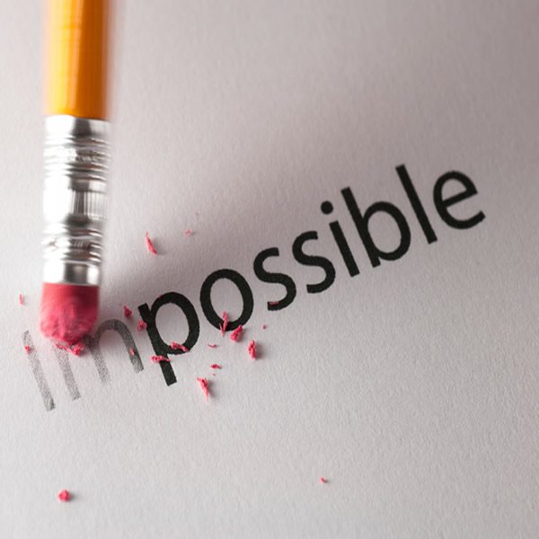 Erasing the word impossible with a pencil eraser