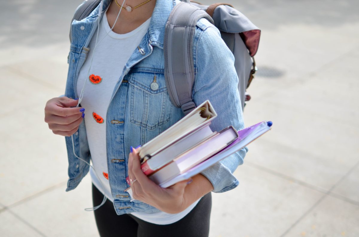 college student with backpack and books in hand