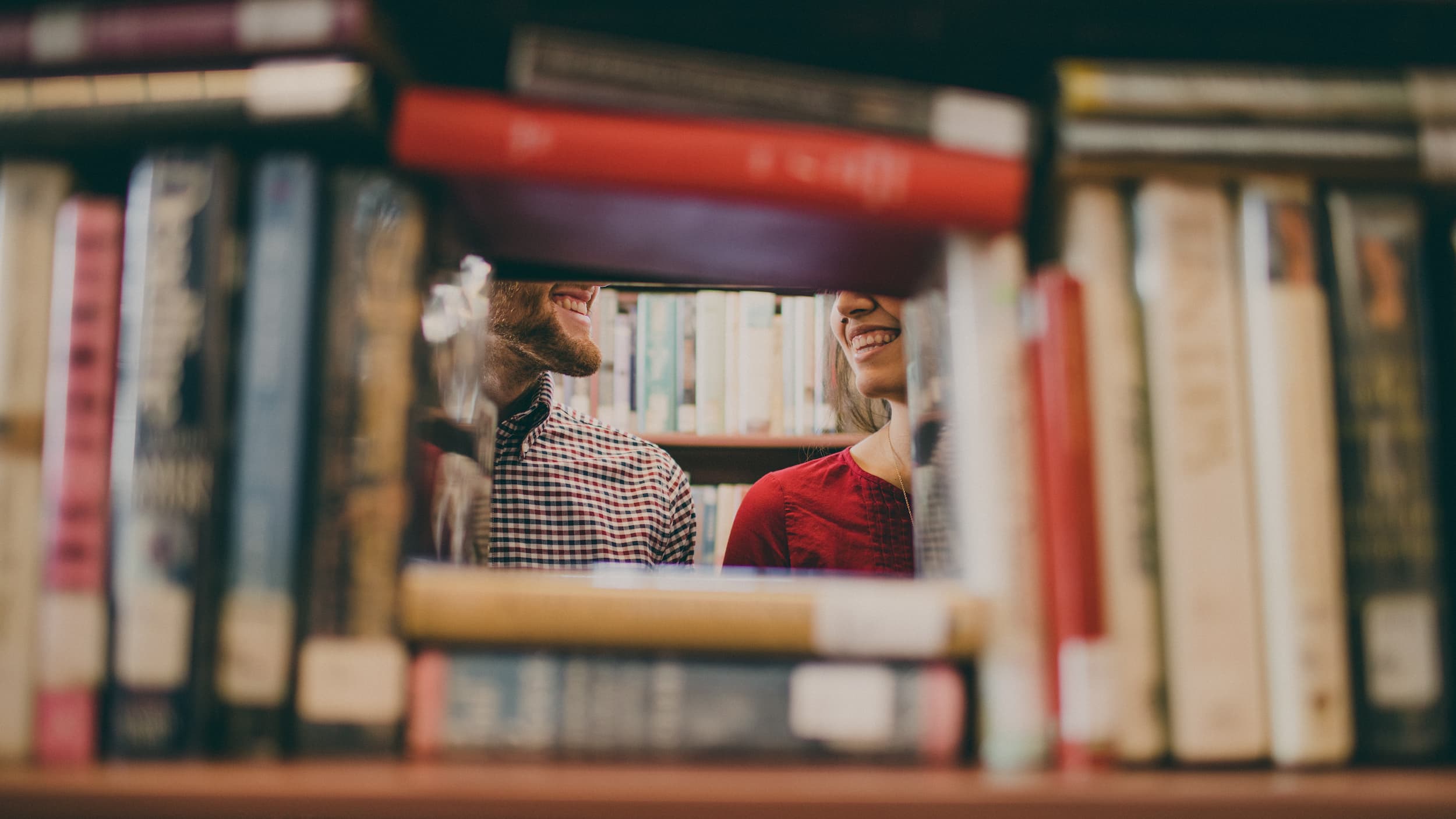 Two people laughing while browsing books in a bookstore