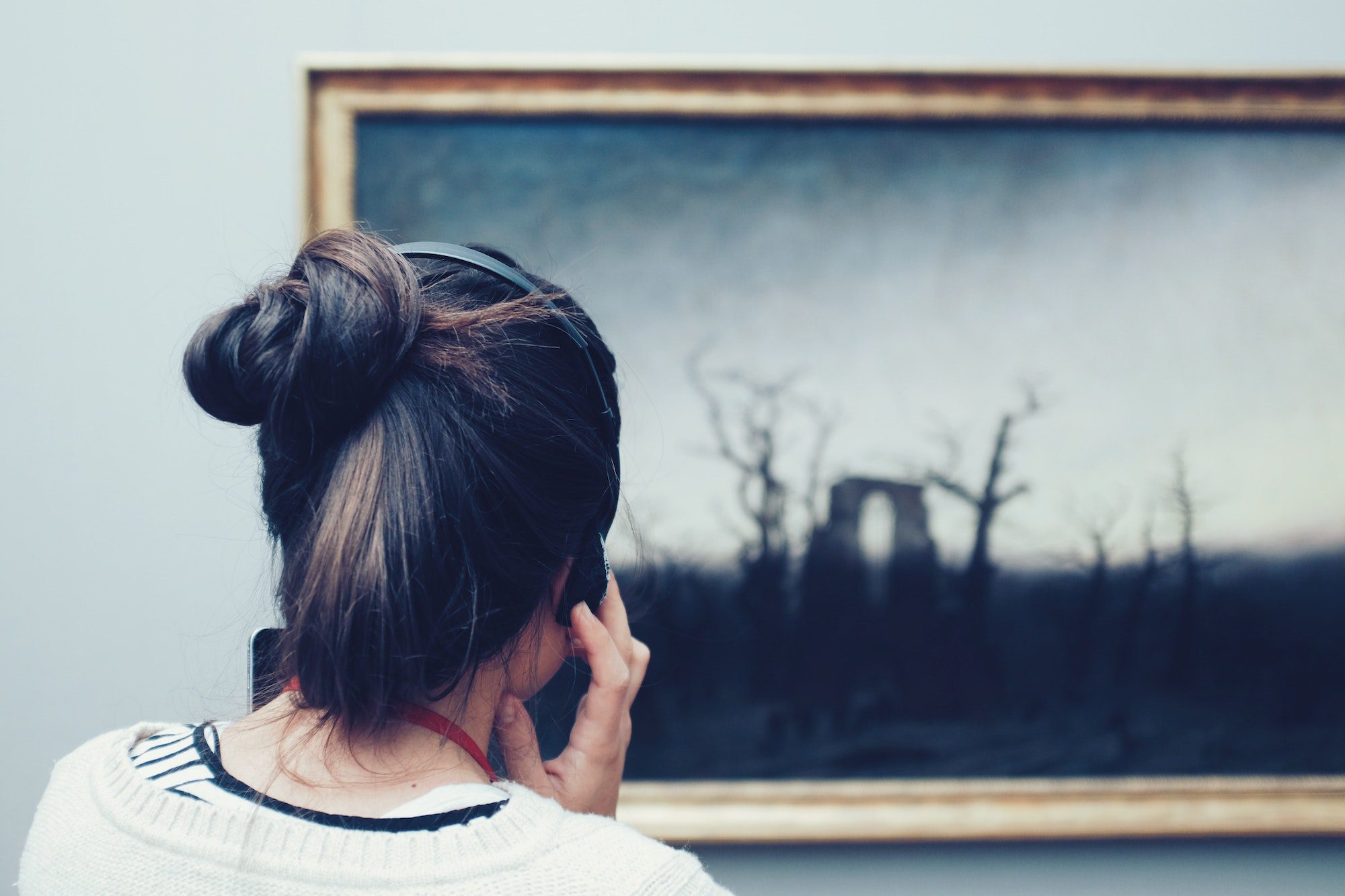 Woman looking at painting on museum wall.