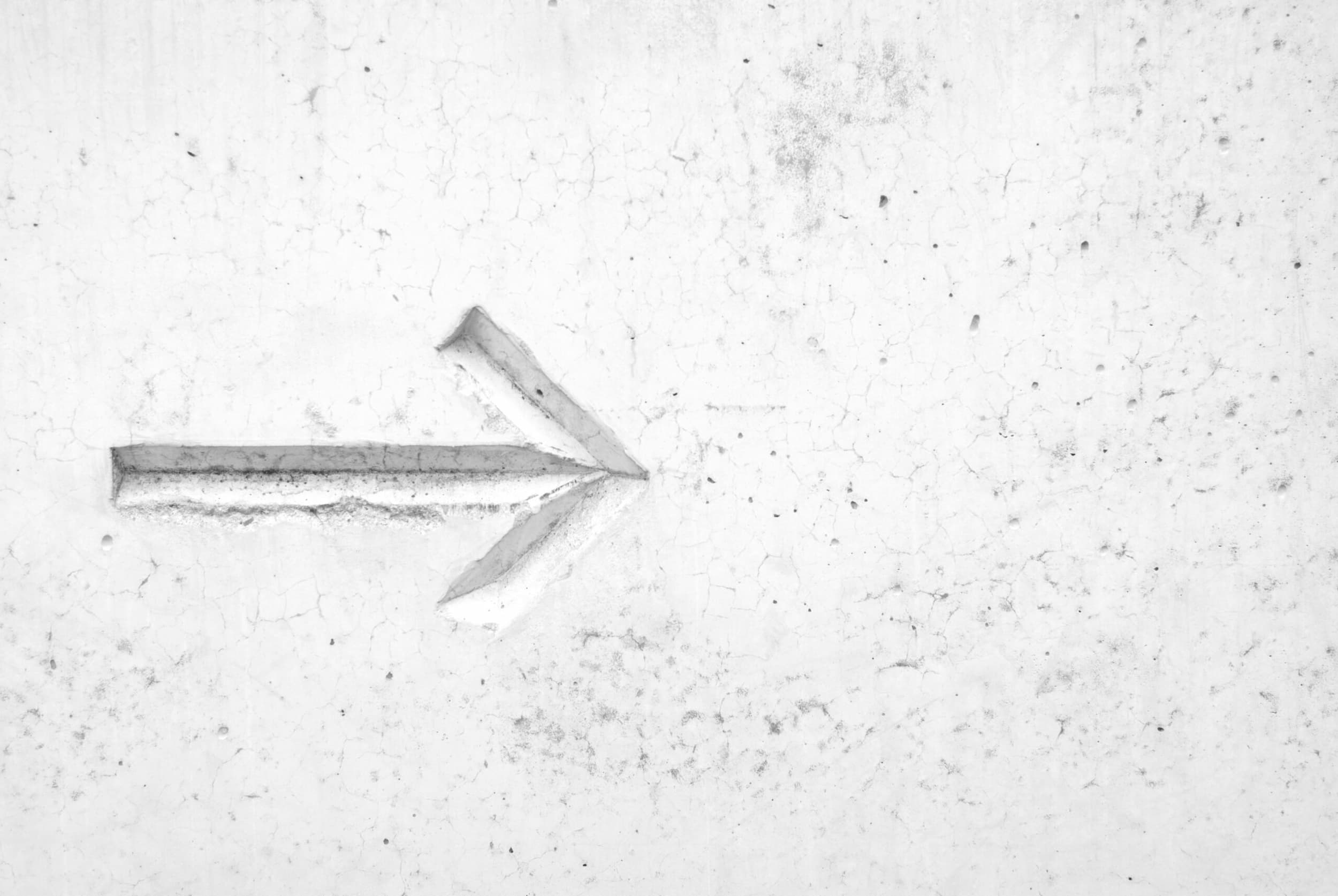 Photo of a white arrow on a white wall