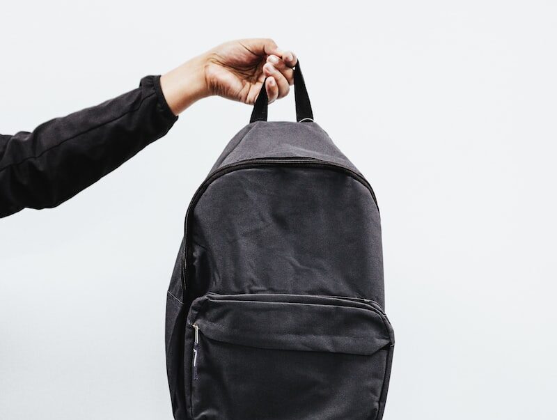 person in black jacket holding black backpack