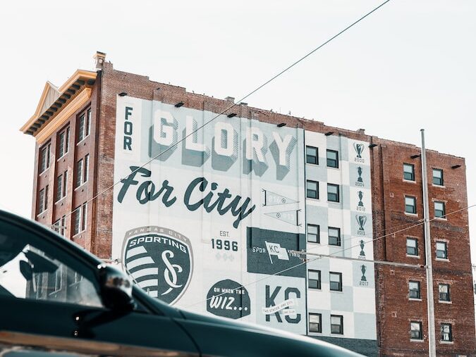 black car parked beside white and brown concrete building during daytime