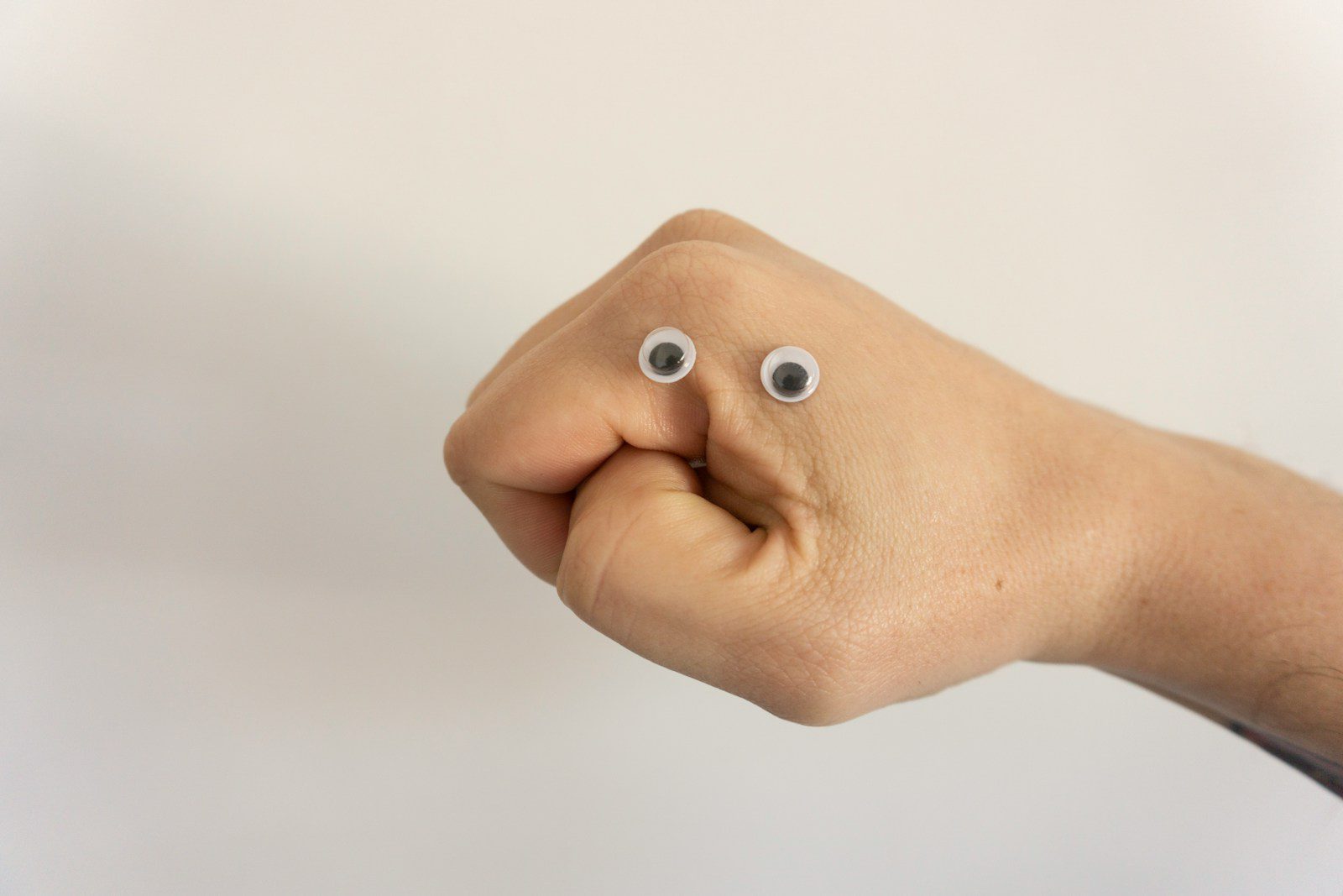 A hand with googly eyes positioned to look like a face