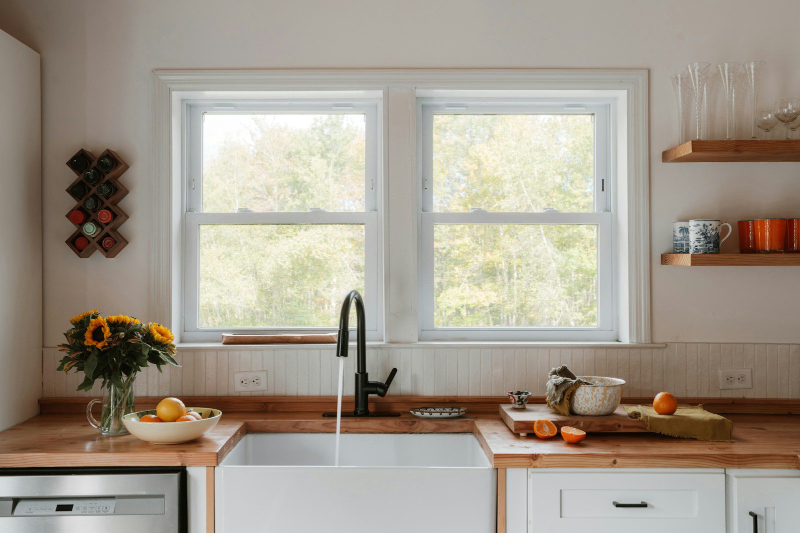 Kitchen sink with sunflowers and fruit on wooden countertop.