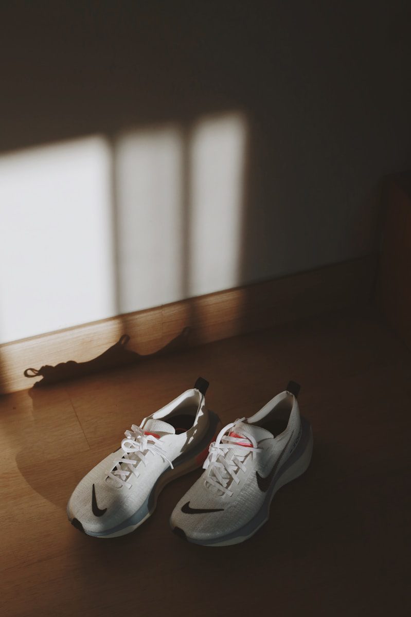 a pair of white shoes sitting on top of a wooden floor