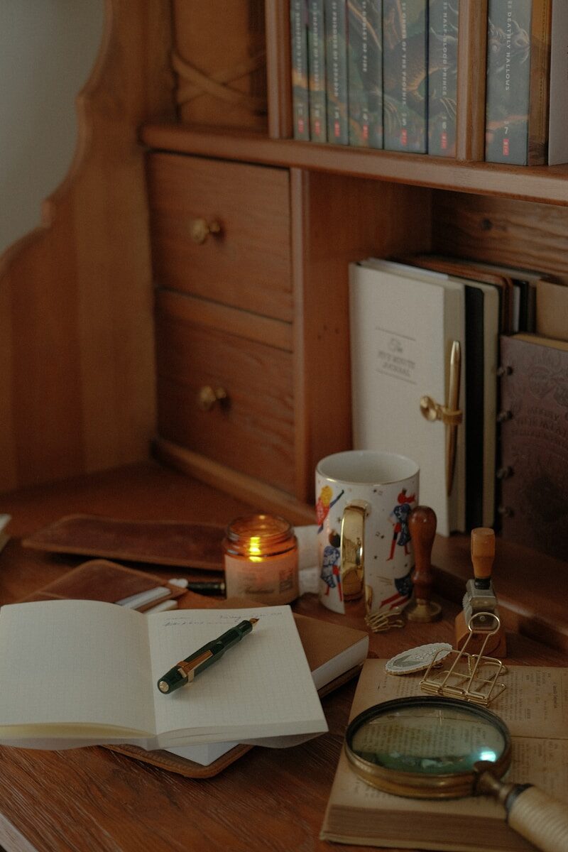 Desk with open journal, pen, candle, and magnifying glass.